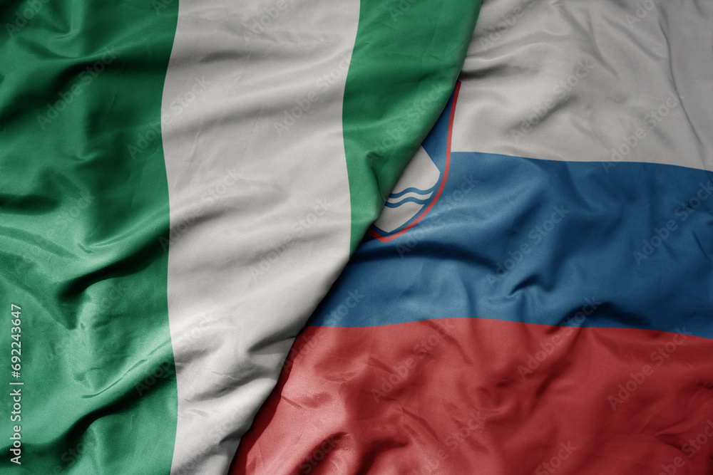 Fototapeta premium big waving national colorful flag of slovenia and national flag of nigeria .