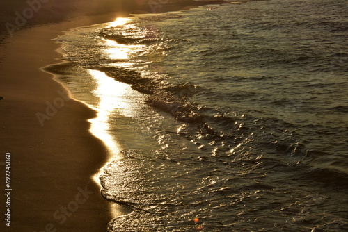Fale na brzegu morza o zachodzie słońca