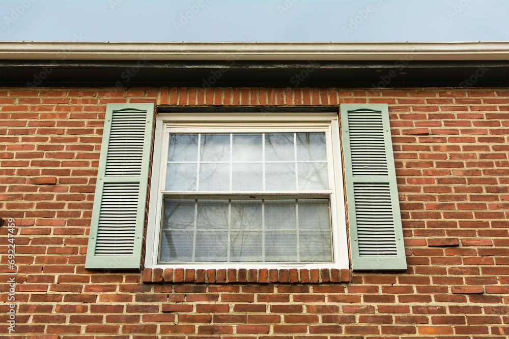 Old house brick wall with new window and fixed decorative shutter, Brighton, MA, USA Old house brick wall with new window and fixed decorative shutter, Brighton, MA, USA