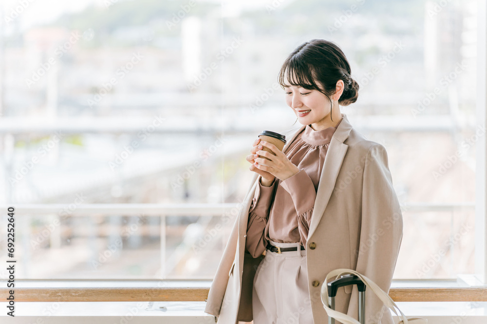 駅・公共施設でコーヒーを飲みながらデートの待ち合わせするビジネスウーマン
