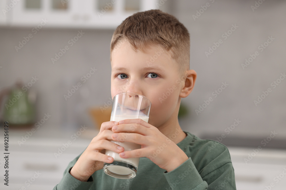 Cute boy drinking fresh milk from glass indoors Cute boy drinking fresh milk from glass indoors