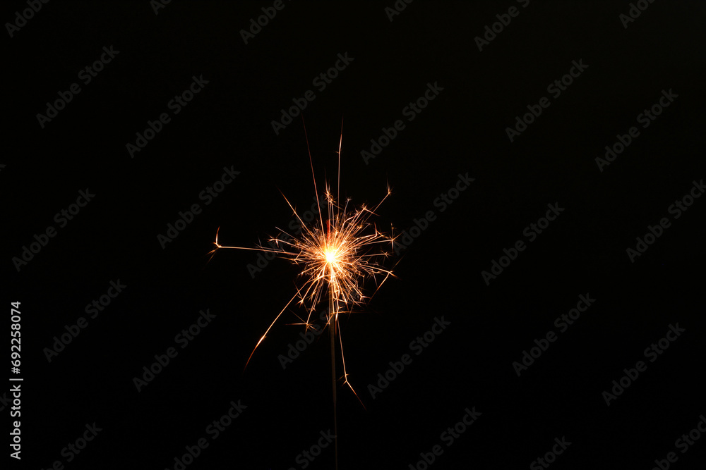 Burning sparkler stick on black background, space for text
