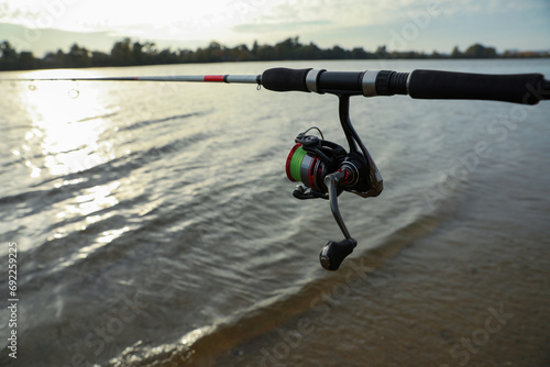 Fishing rod with reel near river, space for text © New Africa