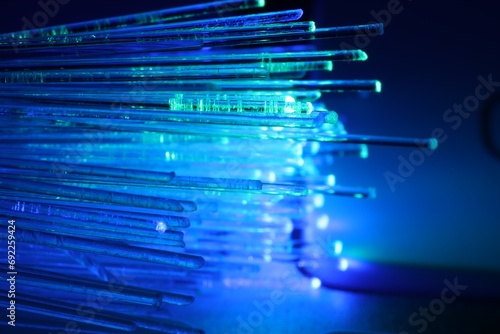 Optical fiber strands transmitting different color lights against blurred background, macro view