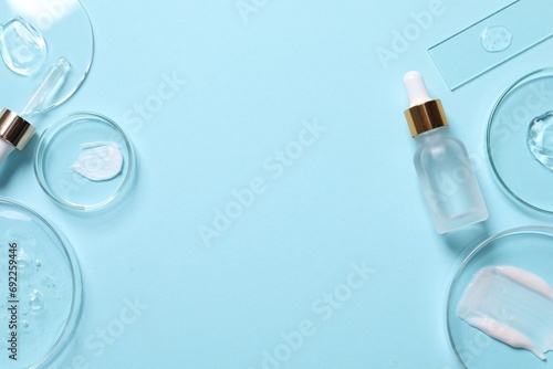 Bottle of cosmetic serum and petri dishes with samples on light blue background, flat lay. Space for text