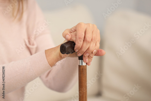 Mature woman with walking cane on blurred background, closeup
