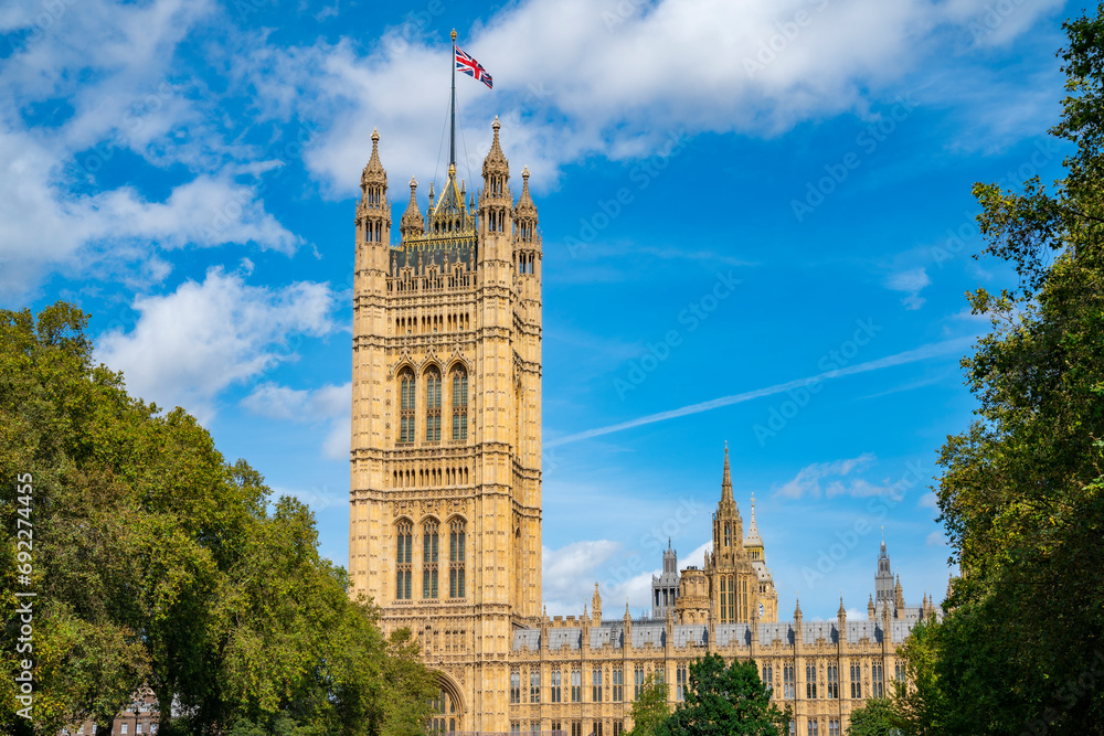 Exterior view of majestic facade of royal palace located near Thames river next to Big Ben against blue sky at evening time in London Exterior view of majestic facade of royal palace located near Thames river next to Big Ben against blue sky at evening time in London