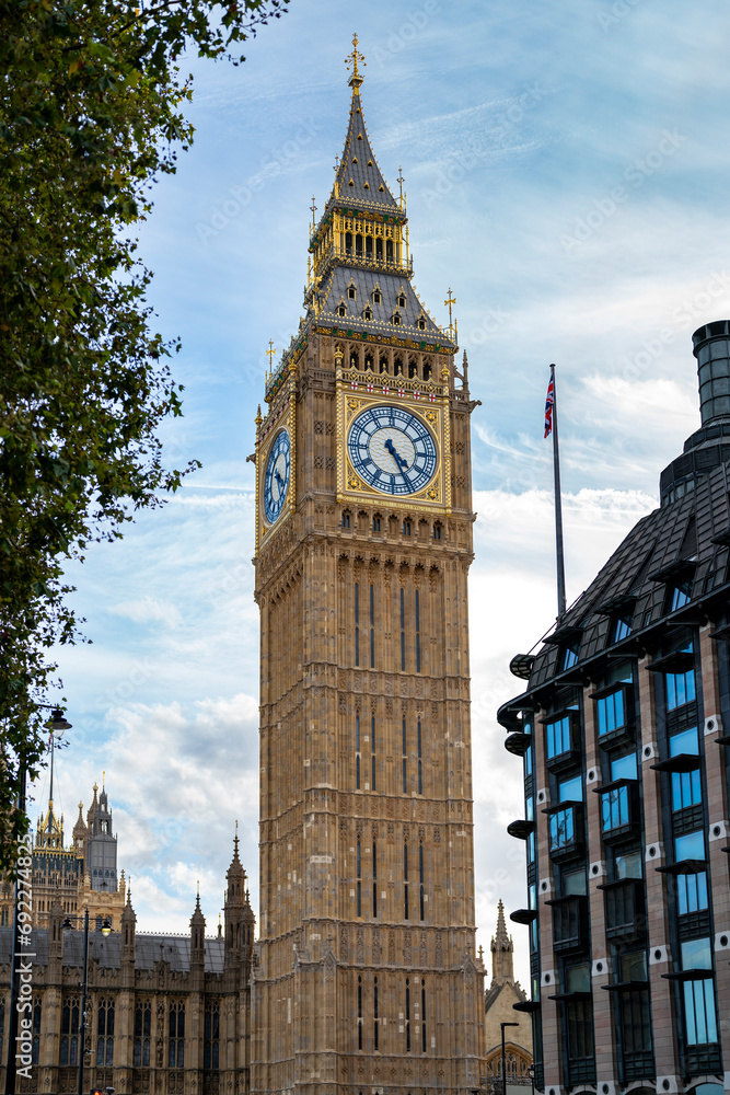 Low angle of aged building of famous Big Ben against clock tower located on street of London against blue sky background