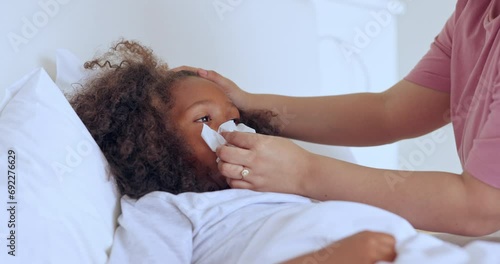 Cold, mother and girl child with tissue to wipe nose or monitor wellness on bed in bedroom of home. Healthcare, woman or hands for medical support, sick or care for ill kid with flu, fever or virus photo