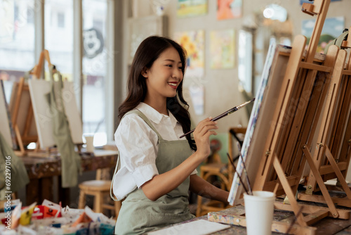 Schilderij op canvas Cheerful young asian woman artist smiling drawing at art studio.