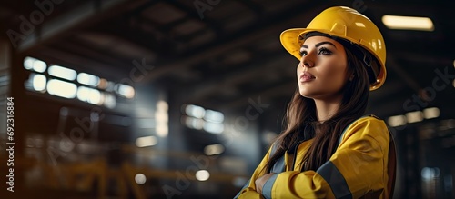 Young female civil engineer in yellow uniform, attentively monitoring construction site indoors. photo