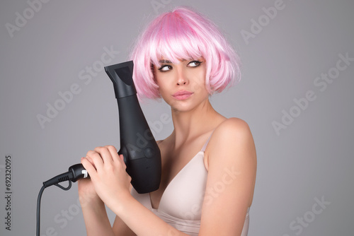 Beautiful young woman using a hair dryer.