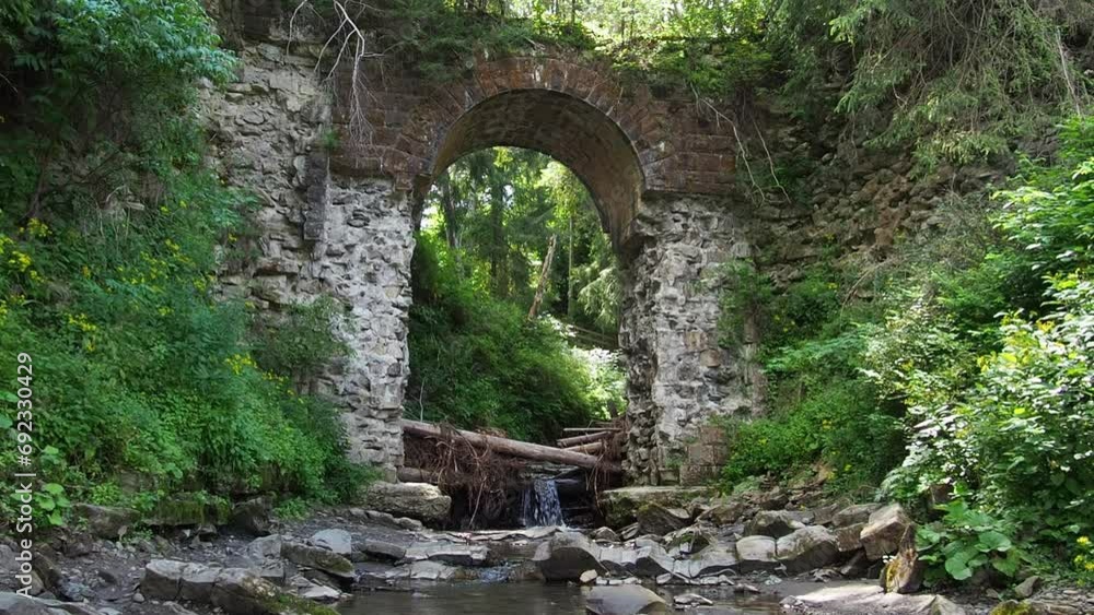 Picturesque ruins of the narrow-gauge viaduct carriage bridge in the village of Vorokhta, Carpathian Mountains, Ukraine. Old stone arched destroyed bridge over small river in a mountain forest. Picturesque ruins of the narrow-gauge viaduct carriage bridge in the village of Vorokhta, Carpathian Mountains, Ukraine. Old stone arched destroyed bridge over small river in a mountain forest.