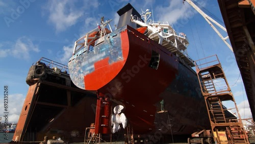 Vessel refurbishment dock, workers apply paint in fast-motion. Aerial view ship restoration hull coating. Industrial maritime repaint, dry dock overhaul. Maritime maintenance, dockyard worker activity