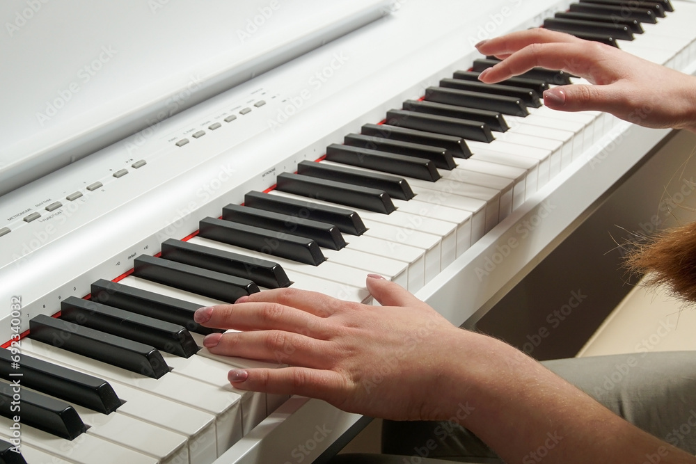 Obraz premium Close-up of a young woman's hands playing an electronic piano.