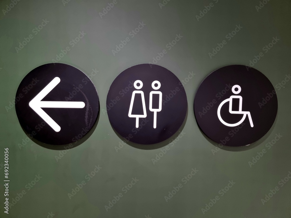 Women's restroom or men's restroom and arrow sign on miscellaneous background.​