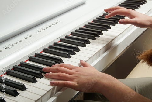 Close-up of a young woman's hands playing an electronic piano.