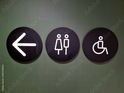 Women's restroom or men's restroom and arrow sign on miscellaneous background.​