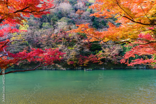 Green color river with red maple leaf autumn foliage at Arashiyama Kyoto Japan.