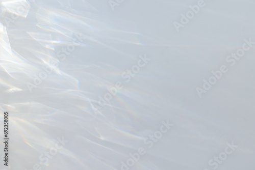  Crystal prism rainbow light refraction texture on white wall background. Organic drop diagonal holographic flare on a white wall. Water shadows for natural light overlay effects photo