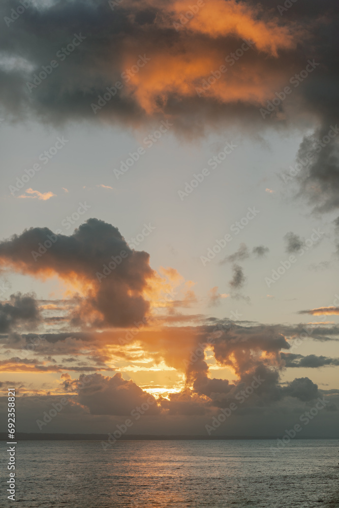 Sunset over Dominican ocean: vibrant orange clouds, tranquil waters.