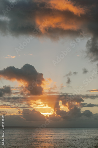 Sunset over Dominican ocean: vibrant orange clouds, tranquil waters.