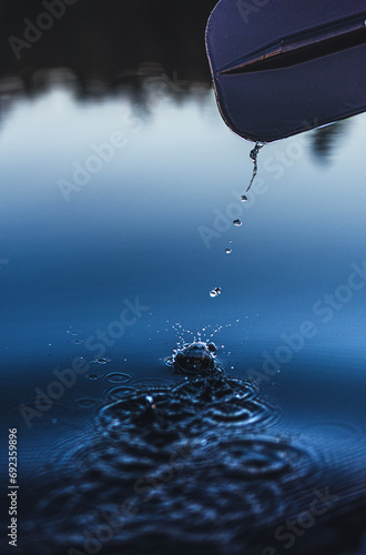 Close up of water dripping off canoe paddle and splashing into lake. photo