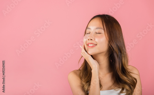 Anti aging. Asian beautiful young woman smiling mask cosmetic patches gel under the eyes, Portrait female applying medical hydrogel eye patch on face, studio shot isolated on pink background, skincare