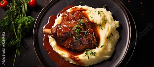 Top view of a design cast iron plate with a modern twist on traditional slow-cooked lamb shank in red wine sauce, served with shallots and mashed potatoes. photo