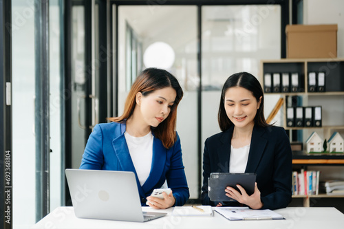 Businesswoman leading team meeting and using tablet and laptop computer with financial in office