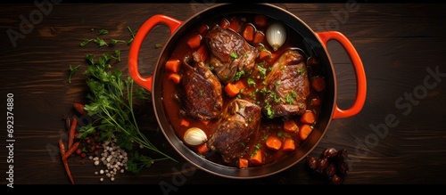 Top view of a stewpot with slow-cooked lamb shank in red wine sauce, shallots, and carrots, representing a modern take on traditional braised lamb. photo