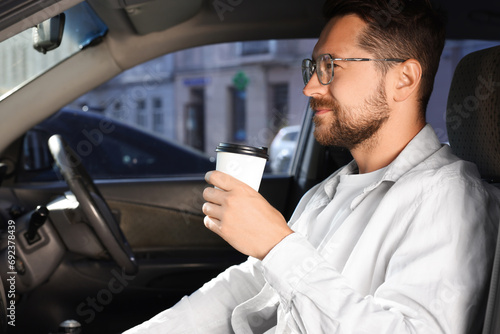 Coffee to go. Handsome man with paper cup of drink in car, space for text