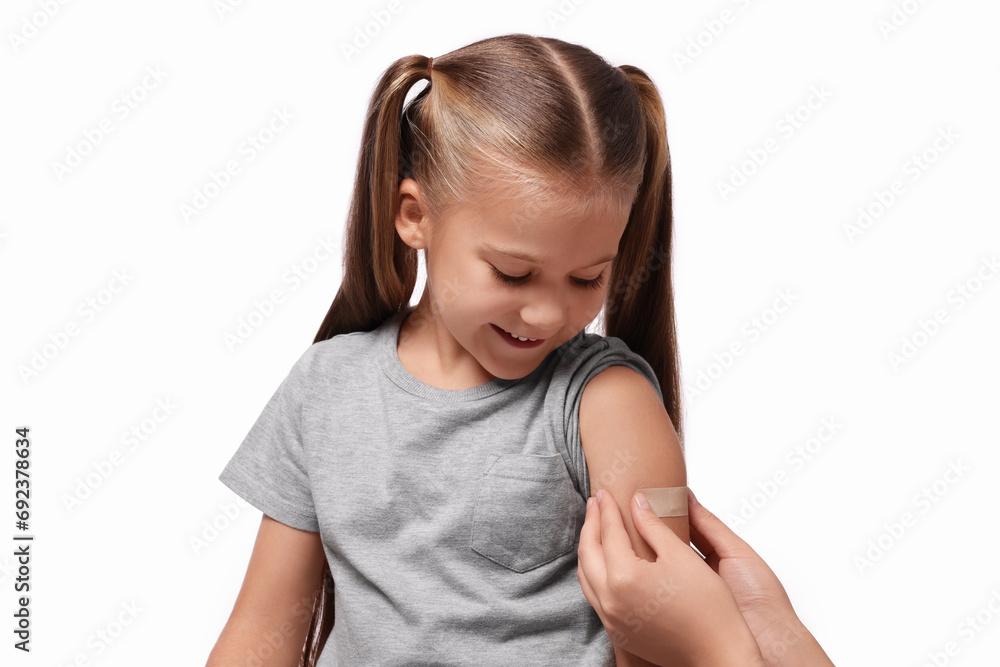 Woman sticking plaster on girl's arm after vaccination against white background Woman sticking plaster on girl's arm after vaccination against white background