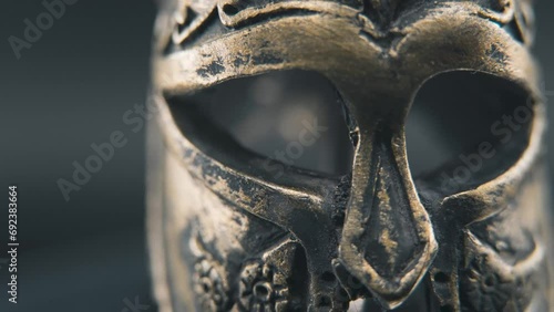 A close up macro professional slow pan right shot of a spartan face design, warrior ancient greek bronze helmet, on a 360 rotating stand, studio lighting, 4K smooth movement photo