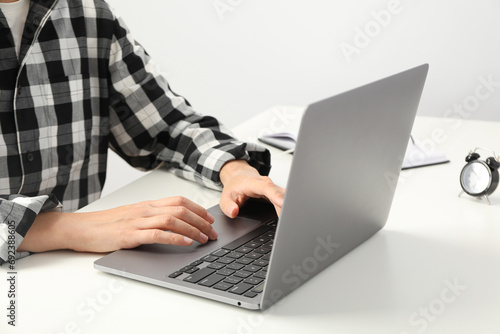 Man's hands on laptop keyboard with glasses and clock