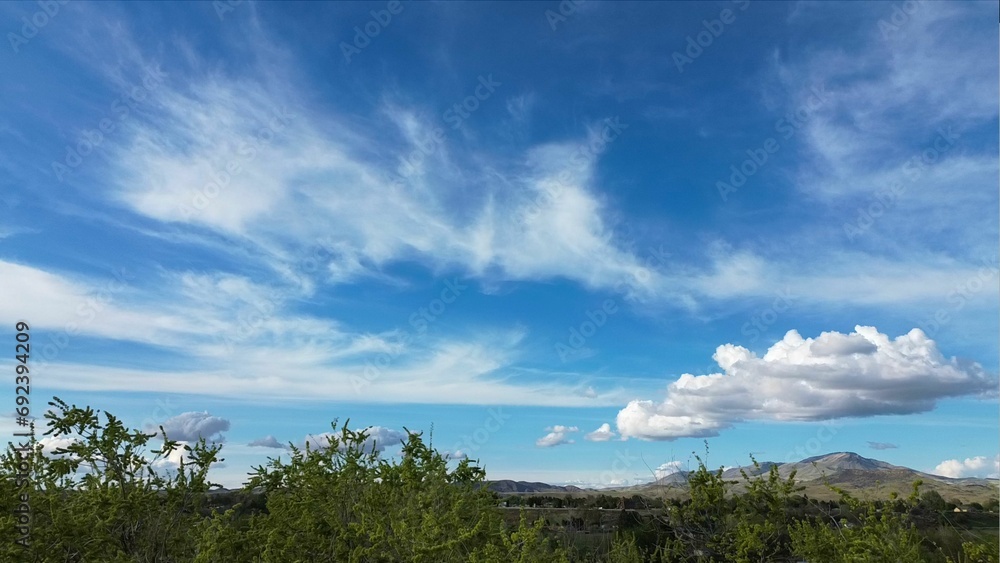 Peaceful landscape featuring a blue sky with white clouds above a distant mountain