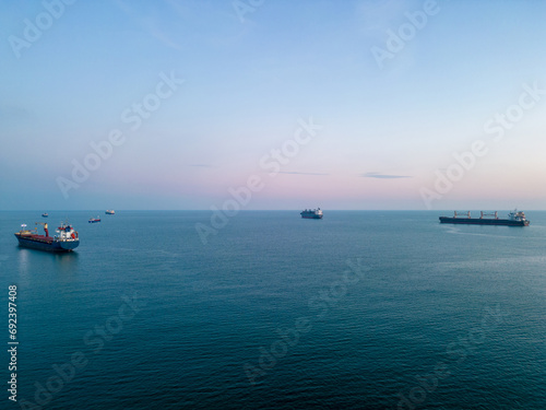 Several cargo ships in a sea bay are waiting in a queue to enter the port  an aerial view