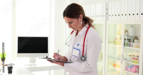 Doctor holds documents in hand and writes medical diagnosis photo
