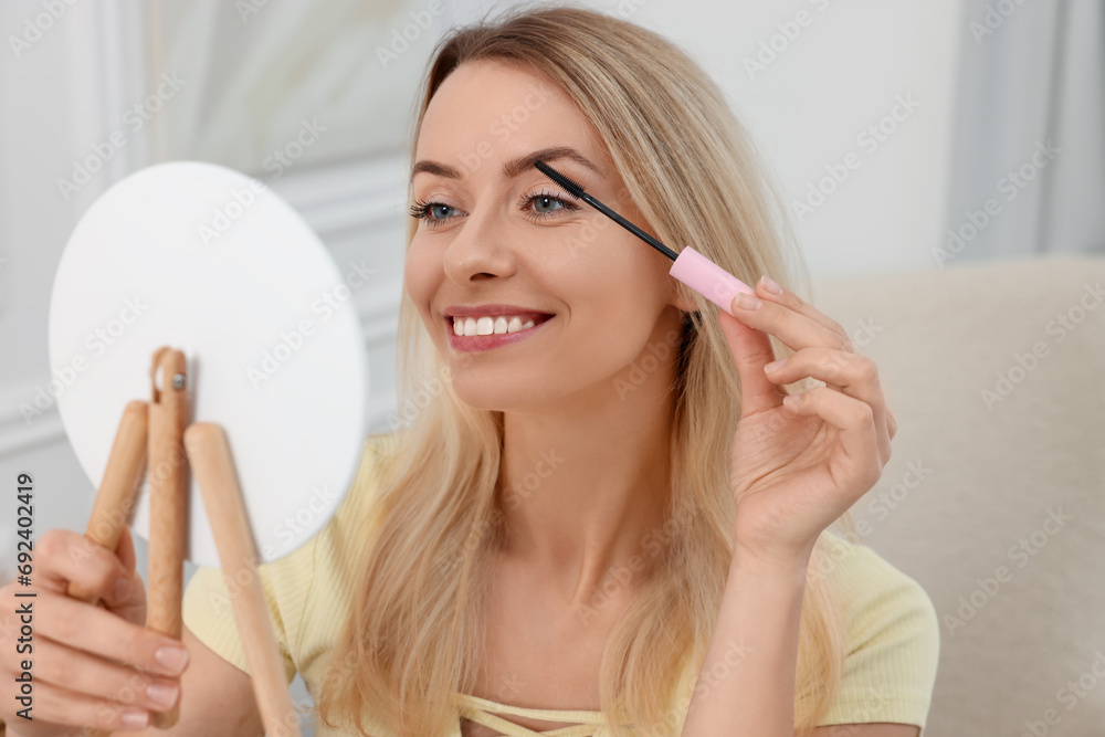 Beautiful woman with mirror applying mascara at home Beautiful woman with mirror applying mascara at home