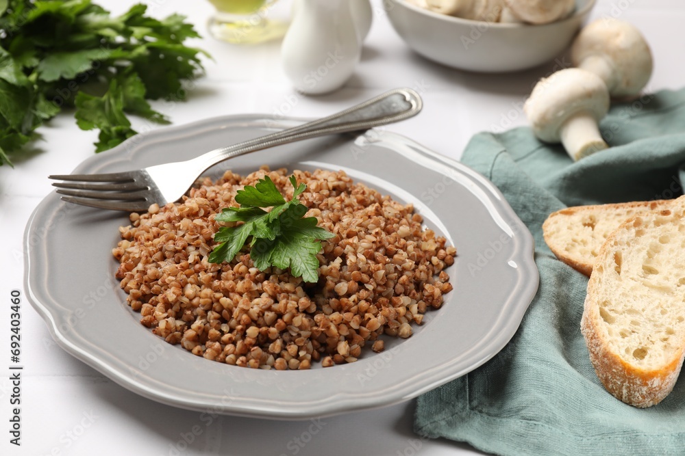 Tasty buckwheat with fresh parsley served on white tiled table Tasty buckwheat with fresh parsley served on white tiled table