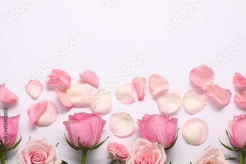 Beautiful pink roses and petals on white background  top view. Space for text