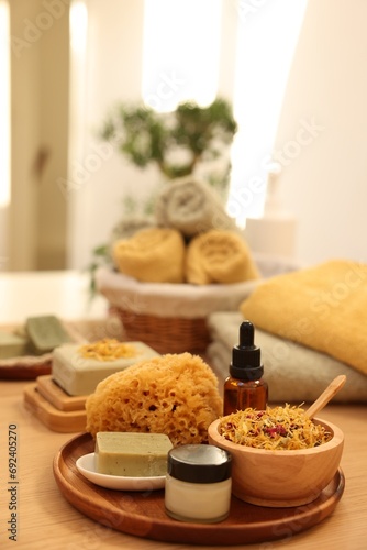 Dry flowers, loofah, soap bar, bottle of essential oil and jar with cream on wooden table indoors, space for text. Spa time