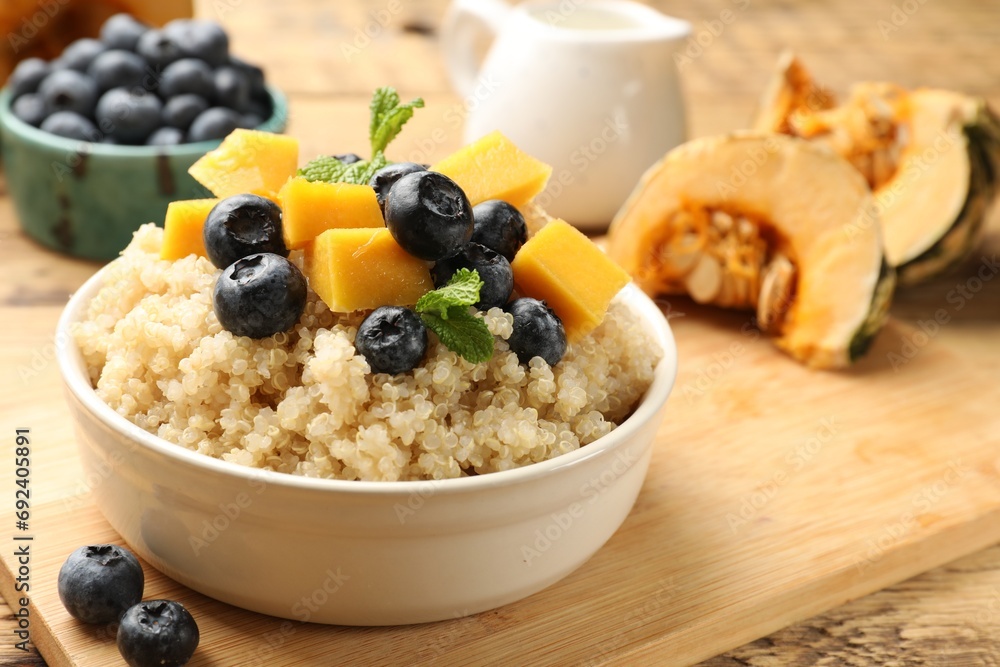 Tasty quinoa porridge with blueberries, pumpkin and mint in bowl on wooden table, closeup Tasty quinoa porridge with blueberries, pumpkin and mint in bowl on wooden table, closeup