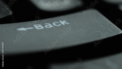 Keyboard button BACK. Macro shot of finger pressing BACKSPACE button photo