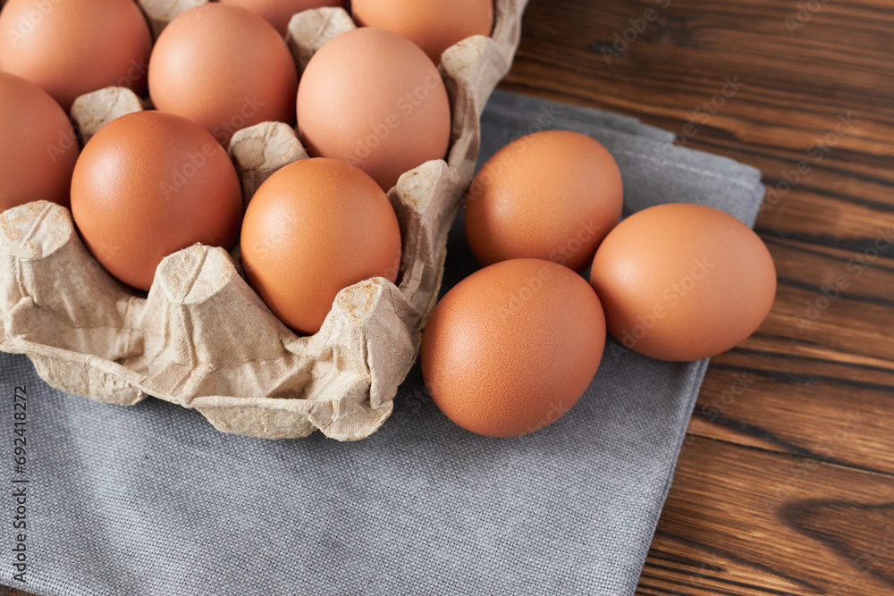 Eggs in a cardboard box on a napkin and a wooden table, close-up Eggs in a cardboard box on a napkin and a wooden table, close-up