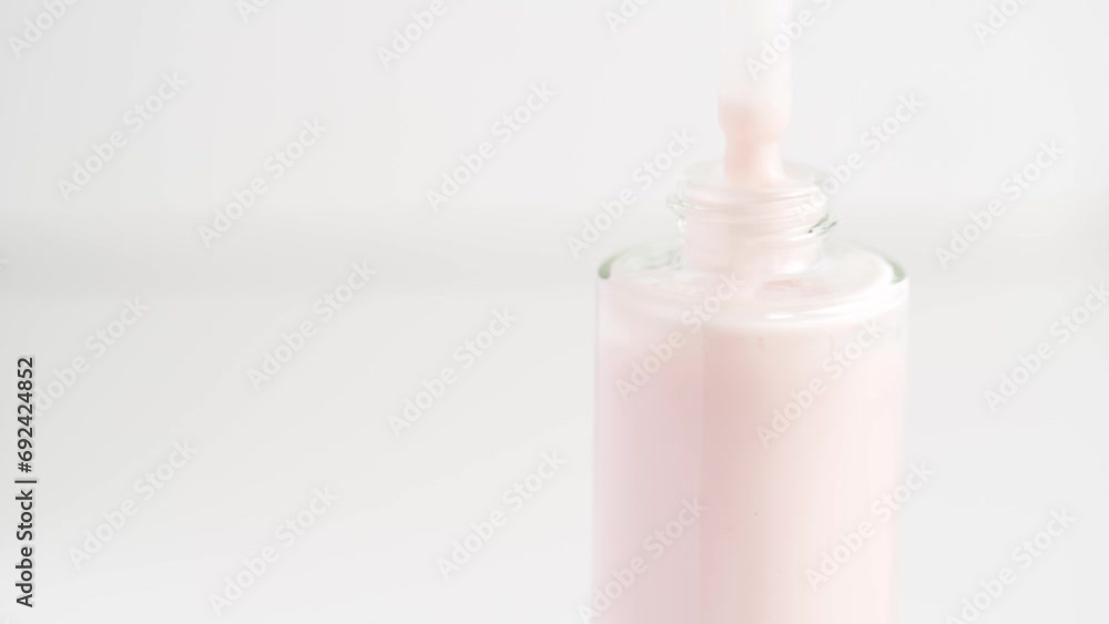 Close up of pipette and the serum bottle. Macro shot of pink moisturizing serum lotion in pipette falling in the bottle. Health care cosmetics. Close up of pipette and the serum bottle. Macro shot of pink moisturizing serum lotion in pipette falling in the bottle. Health care cosmetics.