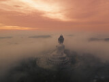 .Colorful first light of the morning covered with mist. Phuket Big Buddha view point.The sun shines on the mist shroud above Phuket Big Buddha. I could see the Buddha image faintly. The sun shines