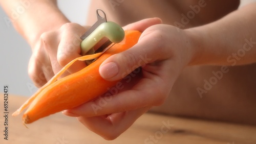 Peeling Fresh Carrot with Peeler. Close-up shot with Shallow DOF.