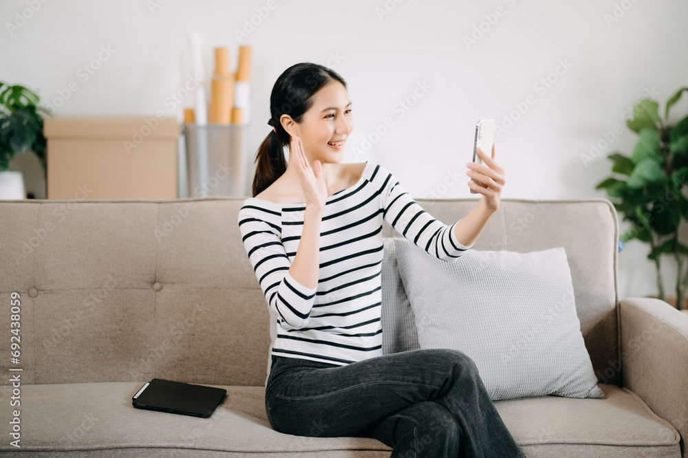 Young asian woman relax on comfortable couch at home texting messaging on smartphone and tablet smiling girl use cellphone shopping online from home Young asian woman relax on comfortable couch at home texting messaging on smartphone and tablet smiling girl use cellphone shopping online from home