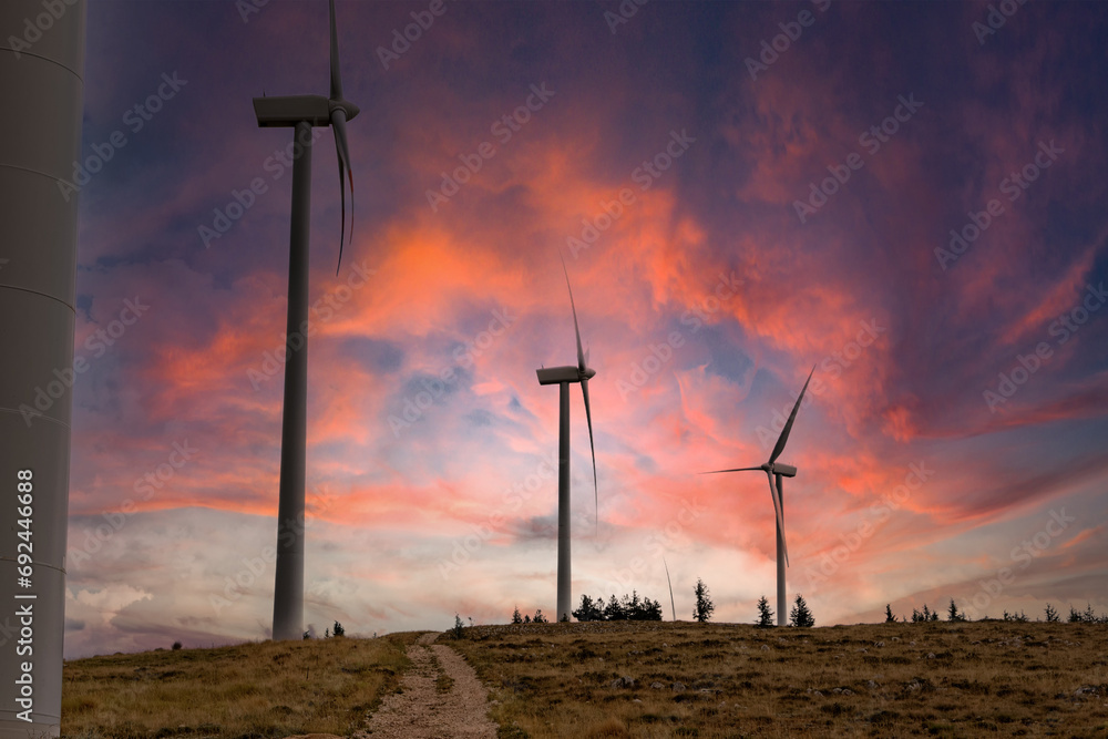 Obraz premium Scenery mountain in winter with a wind farm at sunset Wind turbines for green economy and technology are the only solution to protect the planet from climate change and global warming natural industry